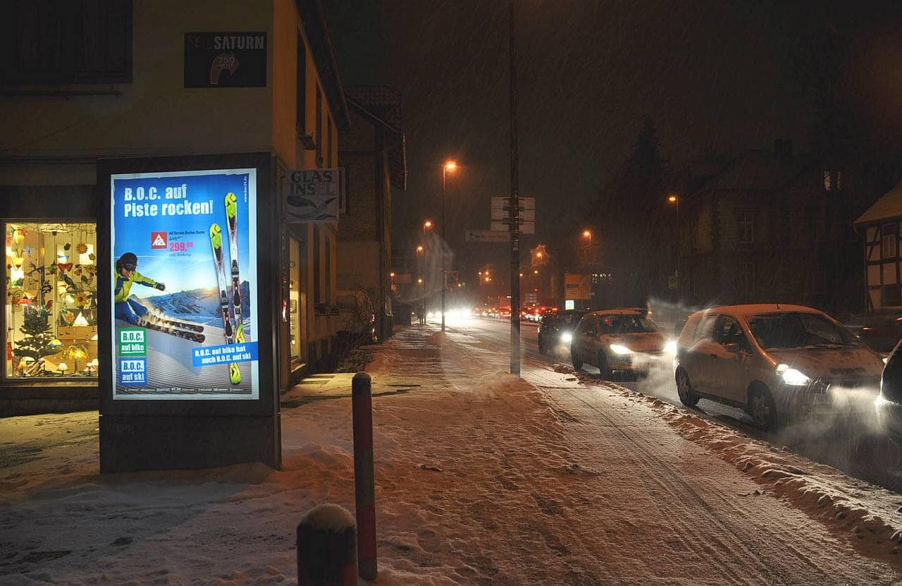 Nachtaufnahme einer beleuchteten CityLightPoster-Vitrine neben einer Straße mit Wartesituation Nachtaufnahme einer beleuchteten CityLightPoster-Vitrine neben einer Straße mit Wartesituation