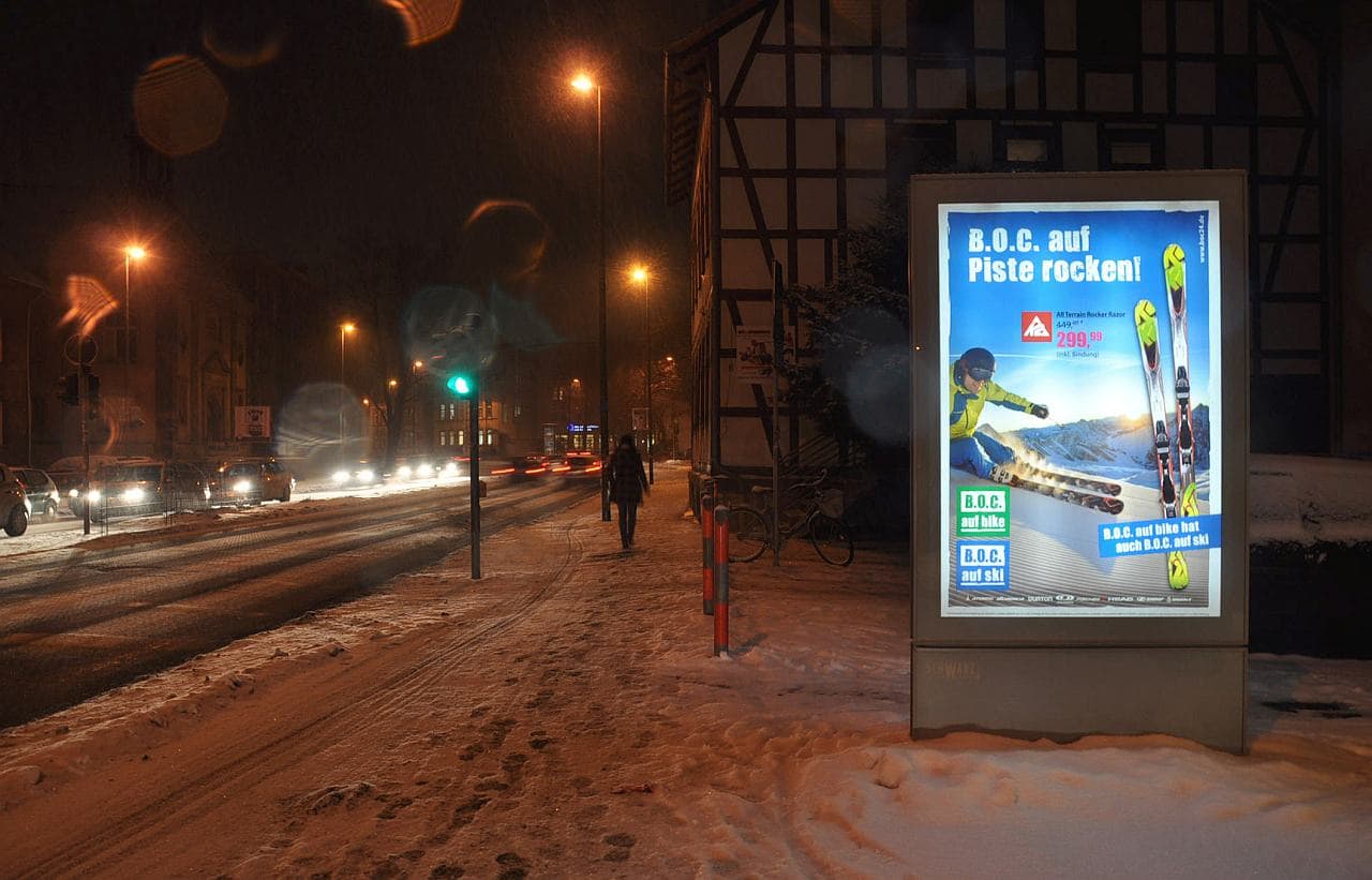 Nachtaufnahme einer beleuchteten CityLightPoster-Vitrine neben einer stark frequentierten Straße Nachtaufnahme einer beleuchteten CityLightPoster-Vitrine neben einer stark frequentierten Straße